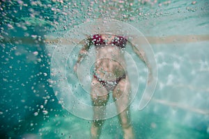 Young woman diving floating in a pool. summer and fun lifestyle. selective focus on bubbles