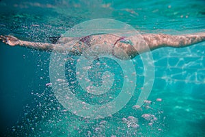 Young woman diving floating in a pool. summer and fun lifestyle. selective focus on bubbles