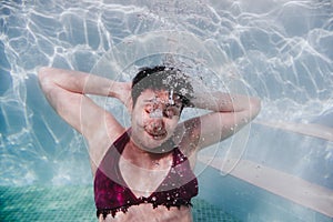 Young woman diving underwater in a pool. arms resting behind the head. summer and fun lifestyle