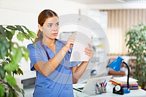 Young woman doctor is attentive studying the patient's outpatient card in the office