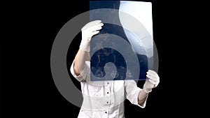 A young woman doctor checks the results of an MRI scan of a spine. A woman examines an MRI image then shows a thumb down