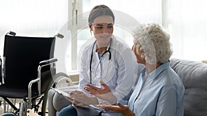 Young woman doctor consulting disabled elderly grandmother