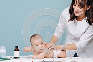 Young woman doctor examines a toddler boy and smiles