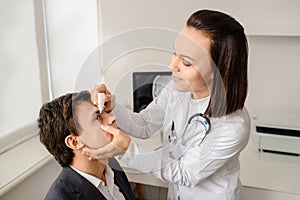 Young woman doctor eye specialist drip drops in patient eye