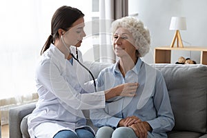 Young woman doctor holding stethoscope examining senior grandma patient