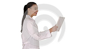 Young woman doctor holding tablet in her hands and making video call on white background.