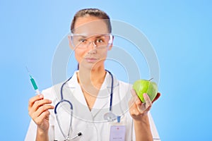 Young woman doctor injecting green apple