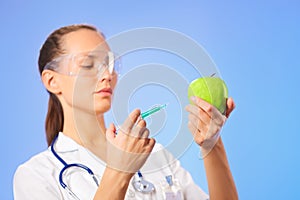 Young woman doctor injecting green apple