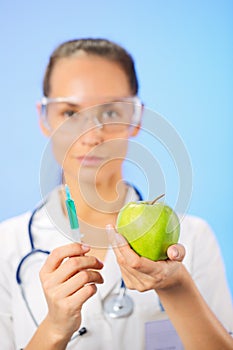 Young woman doctor injecting green apple