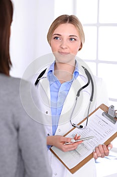 Young woman doctor and patient at medical examination at hospital office. Blue color blouse of therapist looks good