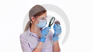 Young woman doctor research COVID-19 virus molecule with magnifying glass