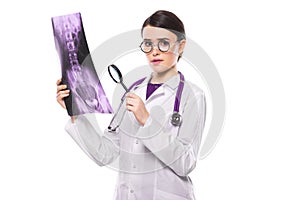 Young woman doctor with stethoscope looking at x-ray making diagnosis in white uniform on white background