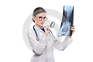 Young woman doctor with stethoscope looking at x-ray making diagnosis in white uniform on white background