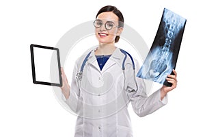 Young woman doctor with stethoscope looking at x-ray making diagnosis in white uniform on white background