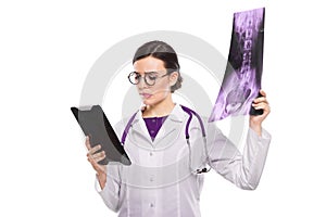 Young woman doctor with stethoscope looking at x-ray making diagnosis in white uniform on white background