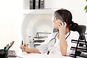 Young woman doctor talking by phone