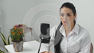 Young woman doctor talking on video chat using mobile at work.