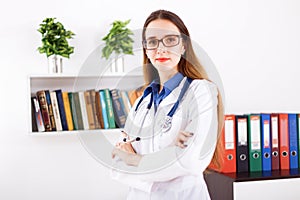 Young woman doctor in white coat standing in doctor`s office