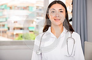 Young woman doctor in white uniform standing in clinic's office