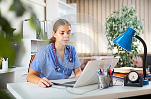 Young woman doctor is working at a computer in the office