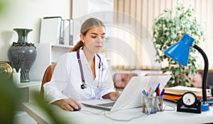 Young woman doctor is working at a computer in the office