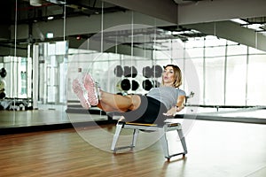 A young woman does abs exercises in the gym on a bench. The concept of sports and a healthy lifestyle