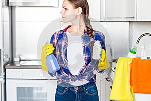 A young woman does the cleaning at home, washes the kitchen. Bucket with rags and yellow gloves on the table