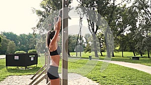 Young woman does various bodyweight exercises at the horizontal bar