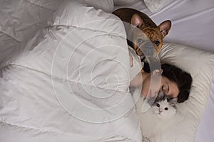 Young woman with dog and cat bask in the morning in her bed