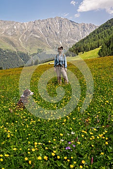 Young woman with a dog on a leash in a natural hiking area on a Tyrolean alpine pasture