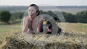 Young woman with a dog in the manger. Portrait of a girl in a field with a terrier.