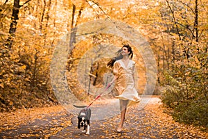 Young woman with the dog in the park. Wind in the hair. With dog on a walk in an autumn nature. Young beautiful female