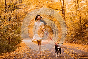 Young woman with the dog in the park. Wind in the hair. With dog on a walk in an autumn nature. Young beautiful female