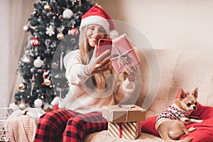 Young Woman and dog in sweater takes selfie portrait on the smartphone at winter holidays, enjoy Christmas time at home