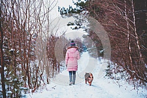 Young woman with the dog walks in the winter forest