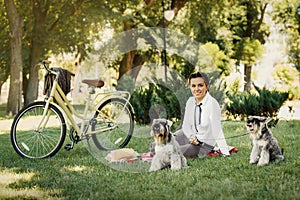 Young woman with dogs and bicycle having picnic in the park