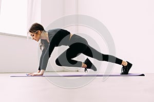 Young woman doing abs workout in a gym on a mat. Sport and lifestyle concept