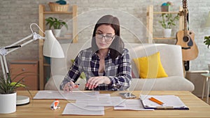 Young woman doing accounting and calculation with calculator on desktop