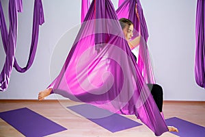 Young woman doing aerial yoga exercise or antigravity yoga indoor.