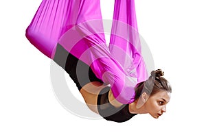Young woman doing aerial yoga exercise or antigravity yoga on a white isolate. Flying, fitness, stretch, balance, exercise and hea