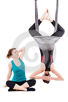 Young woman doing aerial yoga with trainer