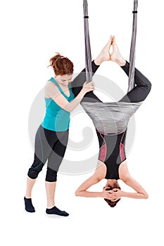 Young woman doing aerial yoga with trainer