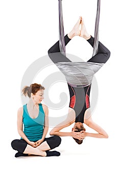 Young woman doing aerial yoga with trainer