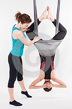 Young woman doing aerial yoga with trainer