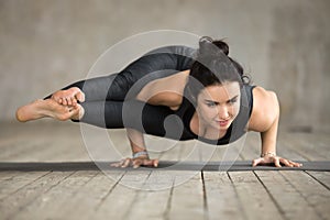 Young woman doing Astavakrasana exercise