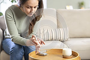 Young woman doing blood sugar test at home