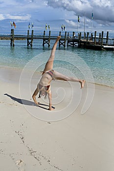 Young woman doing cartwheel on tropical beach