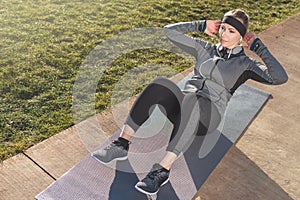 Young woman doing crunches for the abdominal muscles outdoors in