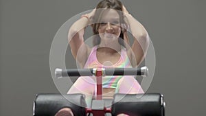 Young woman doing crunches on the bench abs exercising in the gym