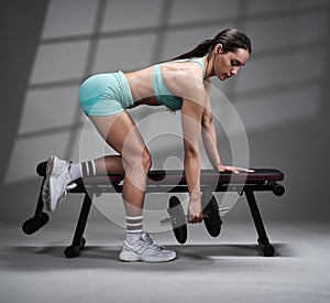 Young woman doing dumbbell row exercise on bench
